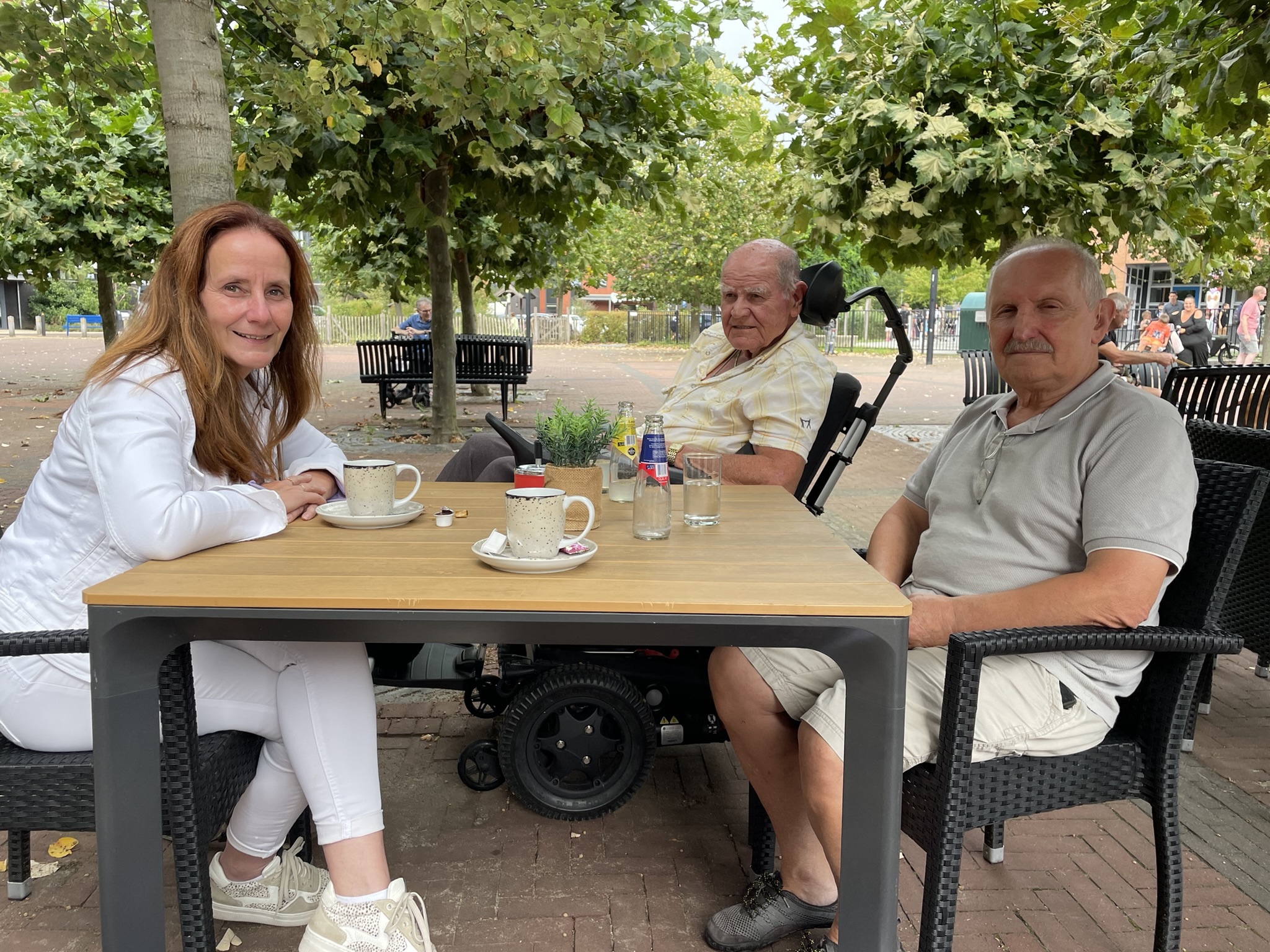 Wethouder Linda van den Beucken met He Naus en Thuisvrijwilliger Seyfullah Saglam buiten aan een tafel